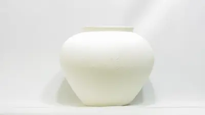 כד לבן מחוספס דמוי בטון.